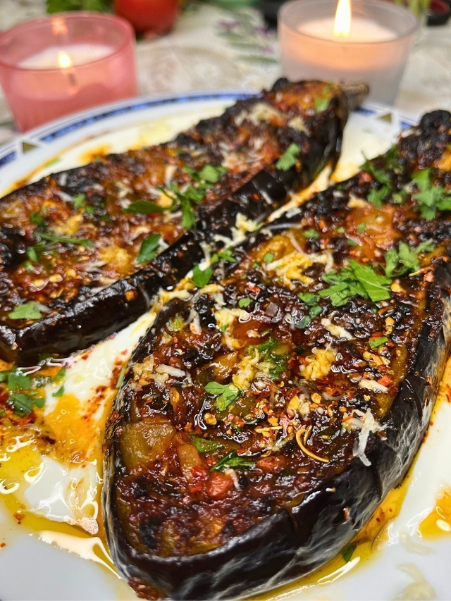 Roasted Garlic Butter Eggplant on a plate with Greek yogurt and candles in the background
